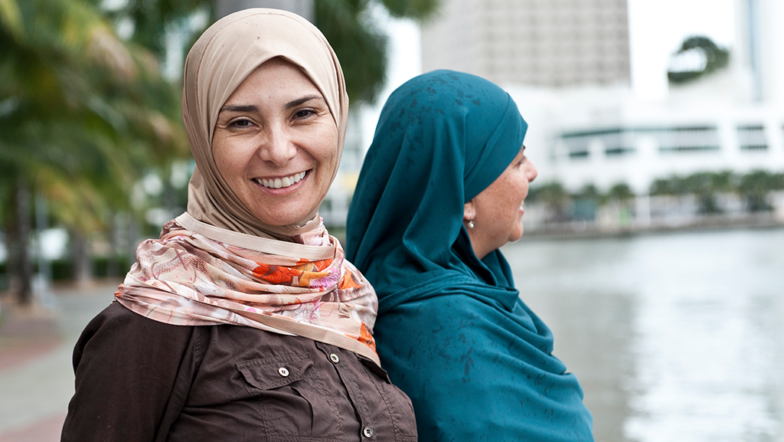 Two women in hijab standing by a river