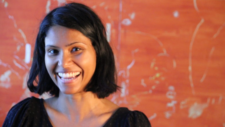 Woman standing against red wall laughing