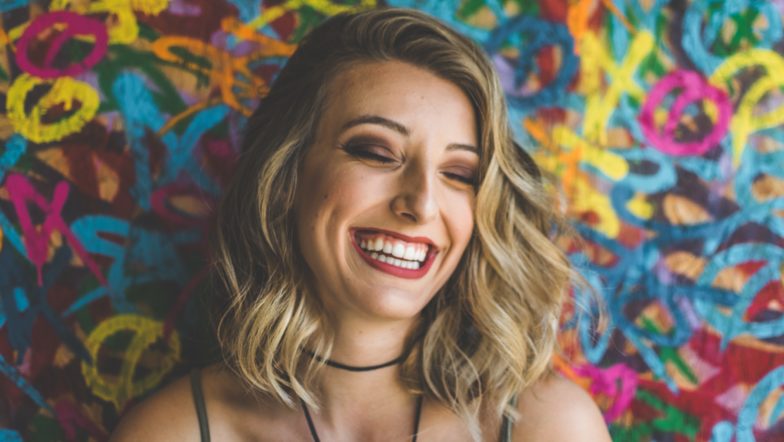 Woman laughing in front of a rainbow background