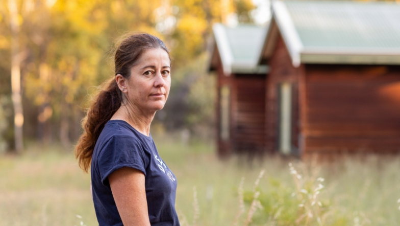 White woman standing in front of small house